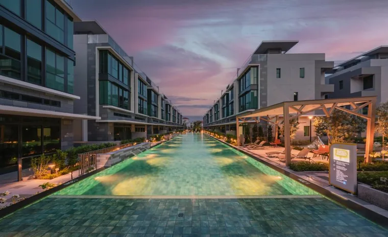 The 50m lap pool at Belgravia Ace lit at night between the house rows